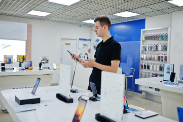 Seller man mobile phone professional consultant in tech store or shop hold new smartphone at  hand.