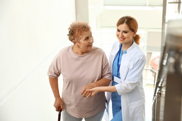 Obraz premium Nurse assisting elderly woman on stairs indoors