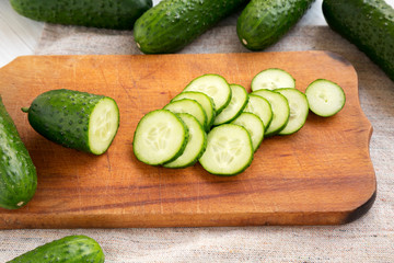Fresh mini baby cucumbers on a rustic wooden board, low angle view. Closeup.