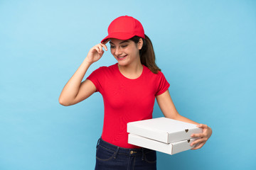 Young woman holding a pizza over isolated pink wall laughing