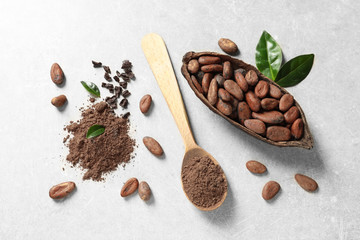 Flat lay composition with cocoa pod, beans and powder on light table
