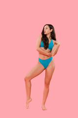 sexy woman in blue swimsuit standing isolated on pink