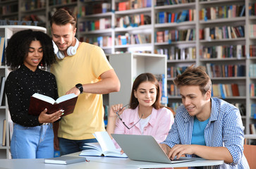 Group of young people studying at table in library