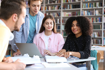 Group of young people studying at table in library