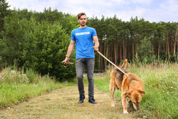 Male volunteer with homeless dog at animal shelter outdoors