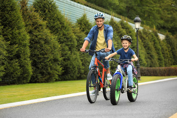 Dad and son riding modern bicycles outdoors