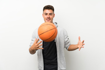 Sport man over isolated white wall with ball of basketball