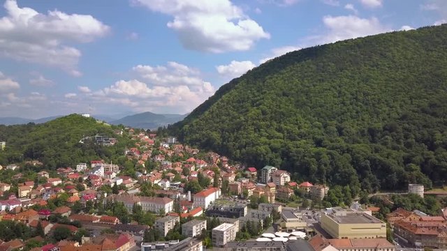 Aerial view of Brasov city, medieval town situated in Transylvania, Romania. Old architecture surrounded with big Carpathian mountains covered with dense green forest.