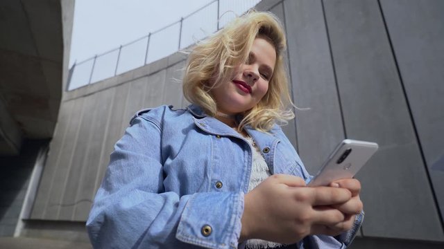Cute overweight girl using messenger app on gadget, generation z lifestyle