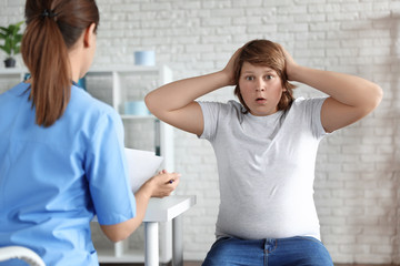 Obraz premium Emotional overweight boy consulting with doctor in clinic