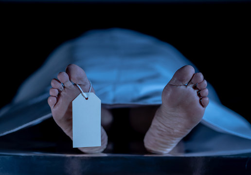 Cadaver on autopsy table at morgue, label tied to toe, close-up