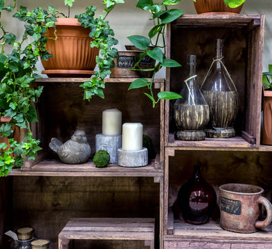 Decorative showcase made from wooden fruit boxes. Flower shop. Vintage composition with potted flowers, vases, candles and etc.