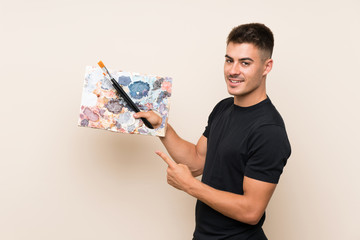 Young artist man over isolated background and pointing it