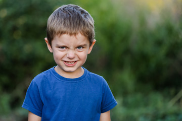 Portrait of a little boy of five years. The cunning, harsh, emotional angry face of a bully child.