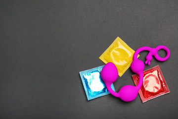 Anal balls and condoms on black background, top view with space for text. Sex game