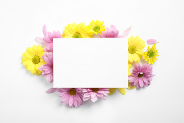 Composition with beautiful chamomile flowers and blank card on white background, top view. Space for text