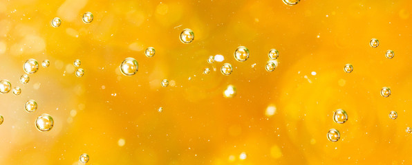 Bubbles of air on the smooth surface of golden water as an abstract background