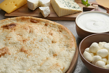 Pizza crust and fresh ingredients on table, closeup