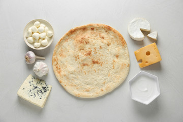 Flat lay composition with pizza crust and fresh ingredients on white table