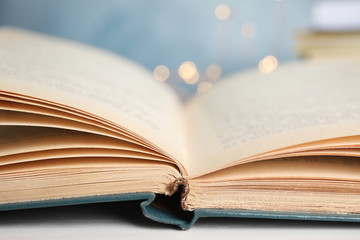 Open hardcover book on table against blurred background, closeup