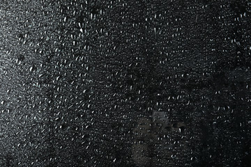 Glass with rain drops against dark background