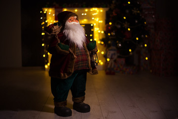 Fototapeta na wymiar Santa Claus carrying big bag full of gifts, at home near Christmas Tree