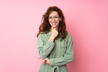 Young pretty woman over isolated pink background with glasses and smiling