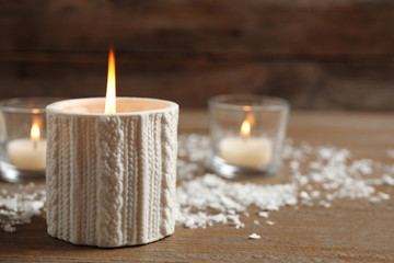 Candle and artificial snow on wooden table, space for text. Christmas decor