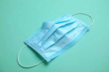 Medical face mask on turquoise background, closeup