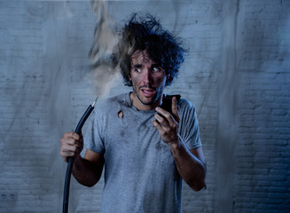 Funny man holding burnt cable calling electrician for help. DIY repairs concept
