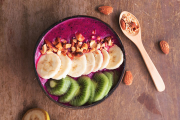 Acai smoothie bowl with superfoods. Smoothy bowl topped with banana, kiwi,and granola almonds on wooden tablw.healthy food concept.