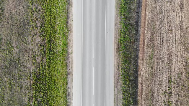 Aerial flying over an empty two-lane highway, on which cars do not pass. Zero traffic. Taken by drone, looking down