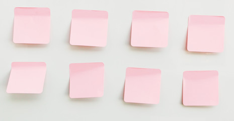 Pink note paper stuck on a white background