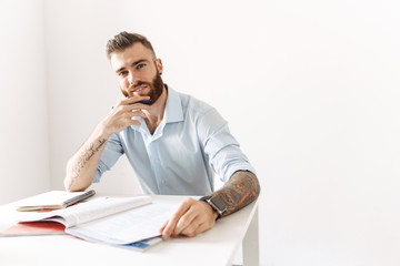 Image of brunette man sitting at table and studying with exercise books