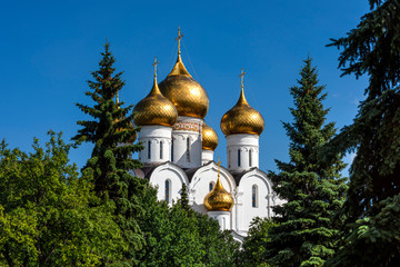 Russia, Golden Ring, Yaroslavl: Famous old onion domed Virgin Mary Ascension Church Cathedral (Maria-Entschlafens-Kathedrale) in the city center of the Russian town with green trees and blue sky.