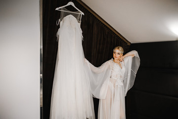 Sexy bride stands near her wedding dress