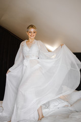 The happy bride in peignoir jumping on the bed