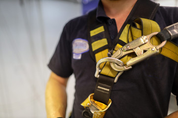 Clipping looking hook onto abseiler fall arrest body safety harness prior to used construction sit...