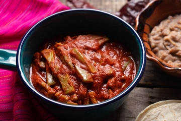 Mexican nopal cactus with guajillo red sauce on wooden background
