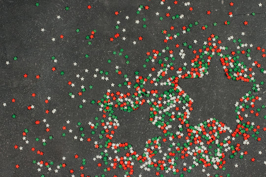  tricolor confectionery confetti in the shape of stars on a dark gray background. decor for Christmas baking.