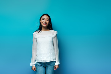 happy brunette asian woman on blue background