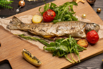 fried trout with arugula, cherry tomatoes and lemon on a board