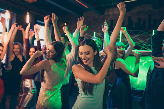 Portrait of positive cheerful elegant girlfriends crowd people celebrate noel party dance on discotheque have fun feel rejoice wearing formalwear dress in green neon lights