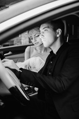 Black and white photo of wedding couple sitting in car