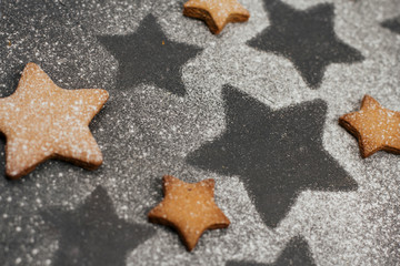  gingerbread cookies sprinkled with icing sugar on a dark gray background with space for text. Christmas baking.