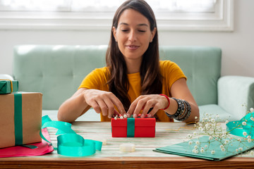 Fototapeta premium Woman wrapping handmade craft gifts on the table at home