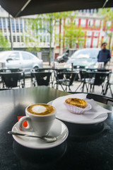 Traditional Egg tart and coffee with milk in a local coffee place in Porto , Portugal  