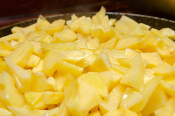 Potato cubes fried in a frying pan close up