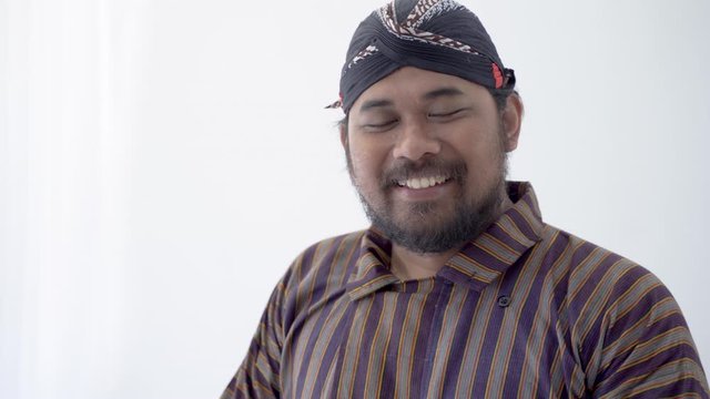 asian man with javanese traditional cloth lurik greeting and smiling to camera