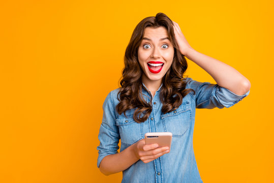 Photo of brunette brown haired curly wavy beautiful casual cheerful excited girl holding telephone reading feednews network expressing emotions with face isolated over yellow vivid color background